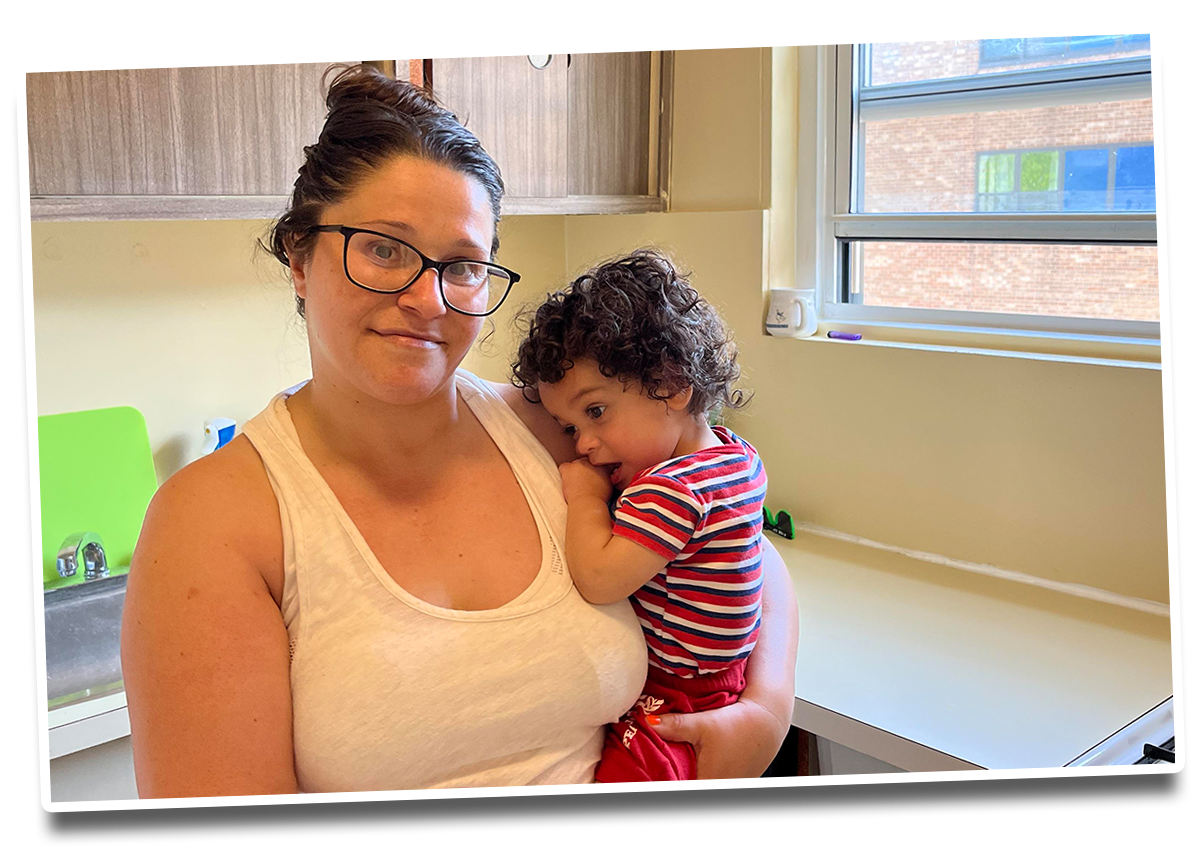 A young woman in glasses holding a baby boy with curly dark hair.